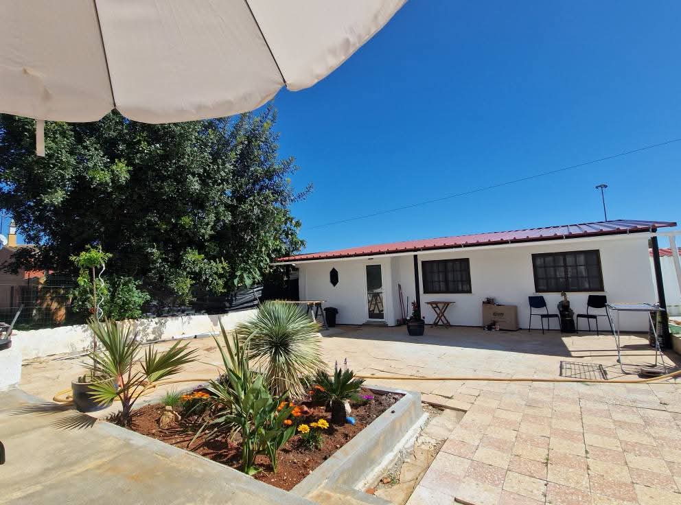 Sunny paved patio and garden outside the Casa Lisa annex with parasol shade